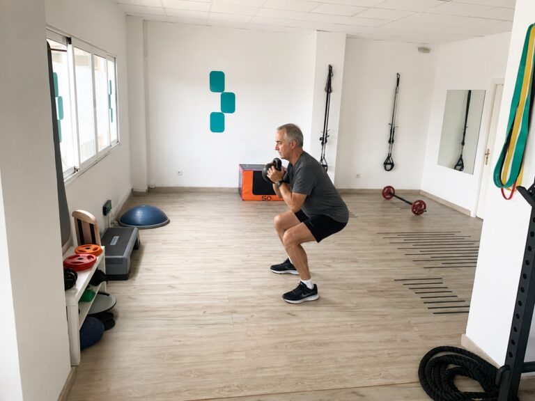 Hombre mayor haciendo sentadilla con kettlebell supervisado en la sala privada de Pila Centro de Entrenamiento, Santander